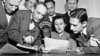 FILE - A group of State Department announcers huddle around the microphone after the initial shortwave broadcast in Russian to Russia from New York City, Feb. 17, 1947.