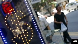 Pedestrians walk past a money exchange outlet in Hong Kong on August 6, 2011