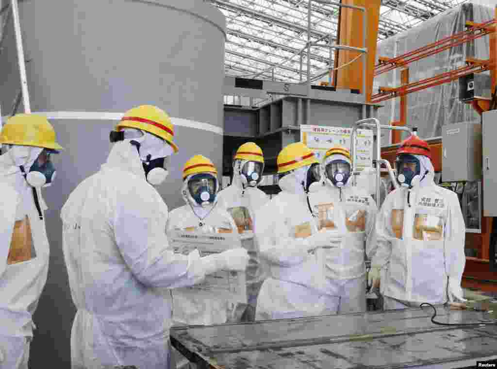 Japan's Prime Minister Shinzo Abe (R) is briefed about water treatment equipment during his inspection tour of the tsunami-crippled Fukushima Daiichi nuclear power plant, Sept. 19, 2013.