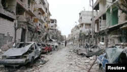 Mobil-mobil dan bangunan-bangunan yang hancur terlihat di kota Douma, Ghouta Timur, Damaskus, Suriah yang terkepung, 25 Februari 2018.