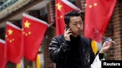 FILE: A smoker puffs while passing a restaurant in Beijing, May 11, 2015. China is enforcing strict new rules on tobacco advertising as of Sept. 1.
