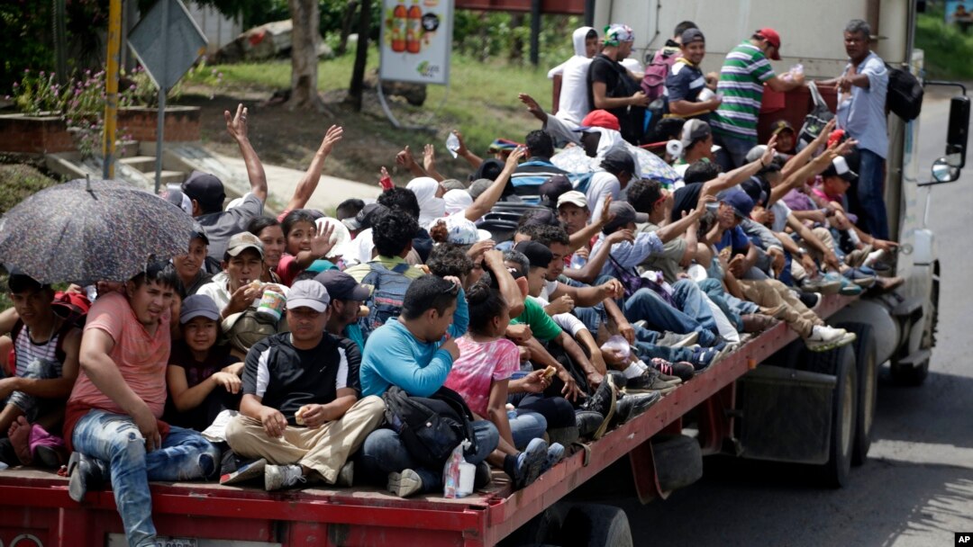 Honduran migrants who are traveling to the United States as a group, get a free ride in the back of a trailer truck flatbed, as they make their way through Teculutan, Guatemala, Oct. 17, 2018.