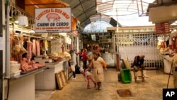 Una mujer sostiene la mano de una niña en un mercado en La Paz, Bolivia, el 28 de junio de 2024, días después de que tropas del Ejército irrumpieran en el palacio de gobierno en lo que el presidente Luis Arce llamó un intento de golpe de Estado.
