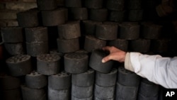 FILE - A man stocks up coal briquettes at his court yard, as many people living in old houses still rely on coal for heat in winter, in Beijing, Nov. 18, 2014. 