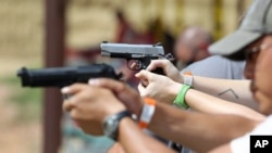 FILE - U.S. gun traders are setting up new websites after Facebook barred private gun sales. Here, shooters practice with pistols at a gun range near Colorado Springs, Colo., July 20, 2014. 