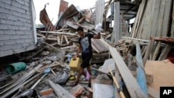 Seorang pria berusaha menyelamatkan barang-barangnya di antara reruntuhan Senin (18/4), sementara isterinya yang hamil dilaporkan tewas akibat gempa di La Chorrera, Ekuador hari Sabtu.