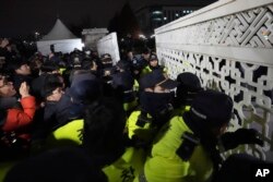 Ljudi pokušavaju da uđu dok polica čuva stražu ispred Narodne skupštine u Seulu, Južna Koreja, 3. decembar 2024.