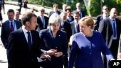 FILE - German Chancellor Angela Merkel, right, speaks with French President Emmanuel Macron, left, and British Prime Minister Theresa May after meeting at a hotel on the sidelines of an EU-Western Balkans summit in Sofia, Bulgaria, May 17, 2018.