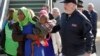 FILE - A woman and child are escorted by a police officer upon their arrival in Pratica di Mare's military airport, near Rome, Nov. 14, 2018. 