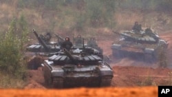 FILE - Russian tanks advance during the Zapad-2017 military exercises near St. Petersburg, Russia, Sept. 18, 2017. Russia is planning large-scale maneuvers dubbed Vostok-2018 in its central and eastern military districts Sept. 11-15, 2018.
