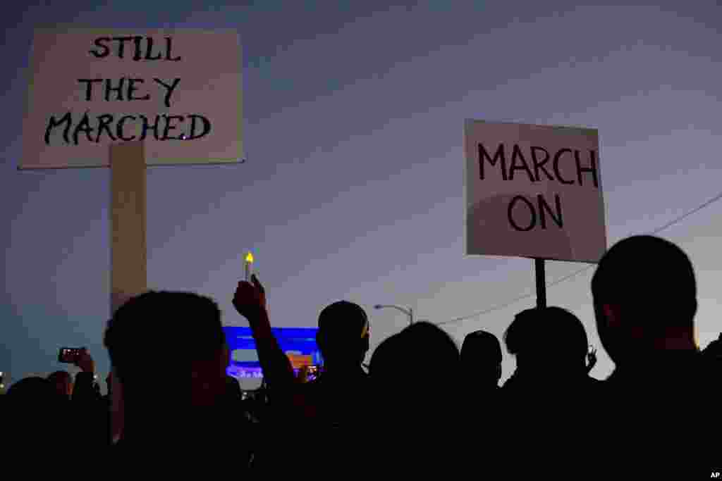 Warga berbaris sambil memegang poster menuju Jembatan Edmund Pettus untuk menghormati Martin Luther King, Jr., di Selma, Alabama (18/1). (AP/Brynn Anderson)