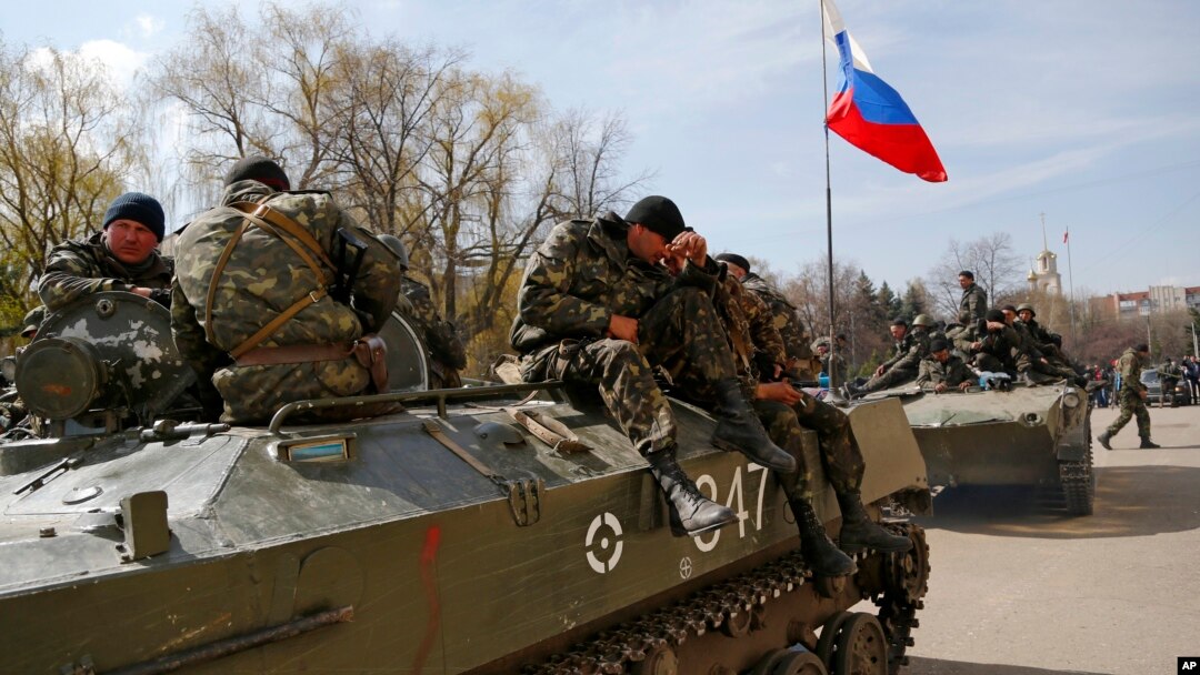Combat vehicles with a Russian flag on one of them and gunmen on top are parked in downtown of Slovyansk, Ukraine, April 16, 2014.