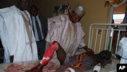 Le gouverneur de l'Etat de Borno, Kashim Shettima, parle à une victime d’un attentat-suicide recevant un traitement dans un hôpital spécialisé à Maiduguri, au Nigeria, 25 novembre 2014. (AP Photo / Jossy Ola)