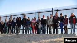 FILE - A group of Central American migrants surrenders to U.S. Border Patrol Agents south of the U.S.-Mexico border fence in El Paso, Texas, March 6, 2019.