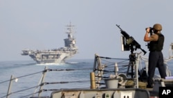 ARCHIVO - El portaaviones USS Dwight D. Eisenhower y otro buque de guerra cruzan el Estrecho de Ormuz hacia el Golfo Pérsico el domingo 26 de noviembre de 2023, como parte del despliegue en Medio Oriente por la guerra entre Israel y Hamás. 