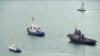 Sebuah kapal Ukraina yang disita (kanan), ditarik oleh kapal penjaga pantai Rusia keluar dari pelabuhan di Kerch, Crimea, Minggu, 17 November 2019. (Krym 24 tv station via AP Television)