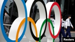 Petugas keamanan berjaga di dekat monumen cincin Olimpiade di luar markas Komite Olimpiade Jepang di Tokyo, Jepang, 18 Mei 2021. (Foto: dok).