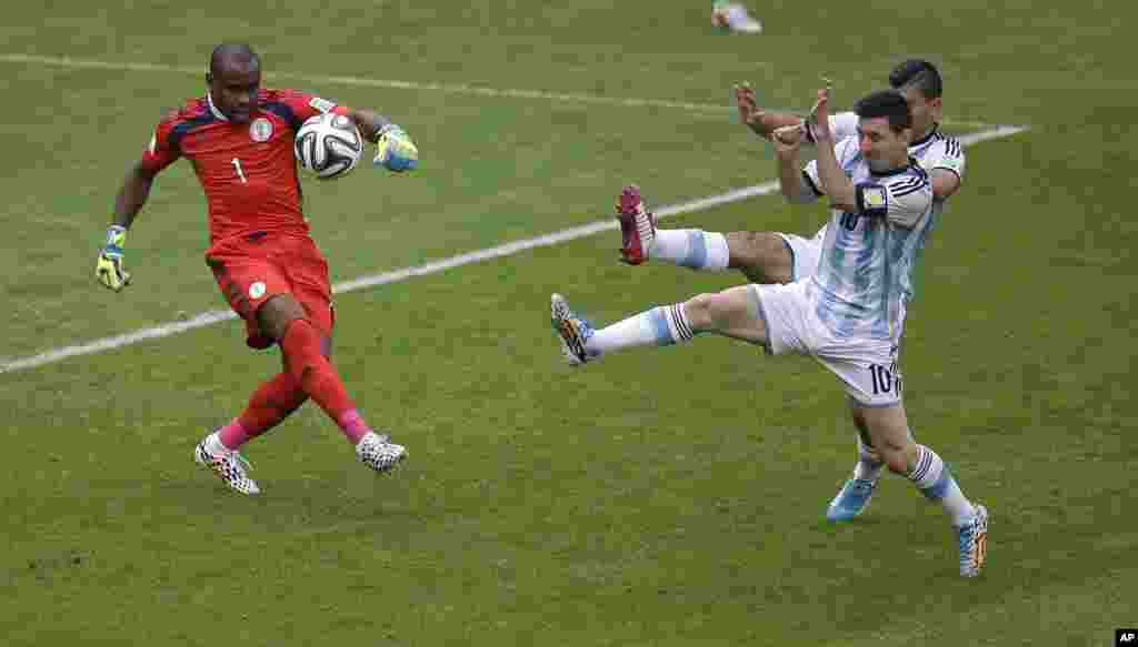Le gardien du Nigeria Vincent Enyeama contrecarre une attaque de Lionel Messi de l'Argentine, devant lui à droite, et Sergio Aguero, lors du match de football Coupe du monde de F de groupe entre le Nigeria et l'Argentine au stade de Beira-Rio de Porto Alegre, au Brésil, mercredi 25 Juin 2014.
