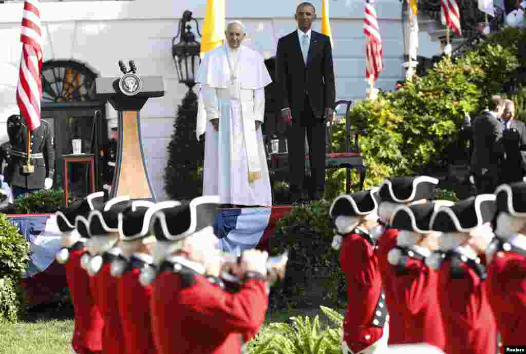 President Barack Obama and Pope Francis watch onstage as the "Old Guard" fife and drum corps marches past during an official welcome ceremony of the South Lawn at the White House, Sept. 23, 2015.