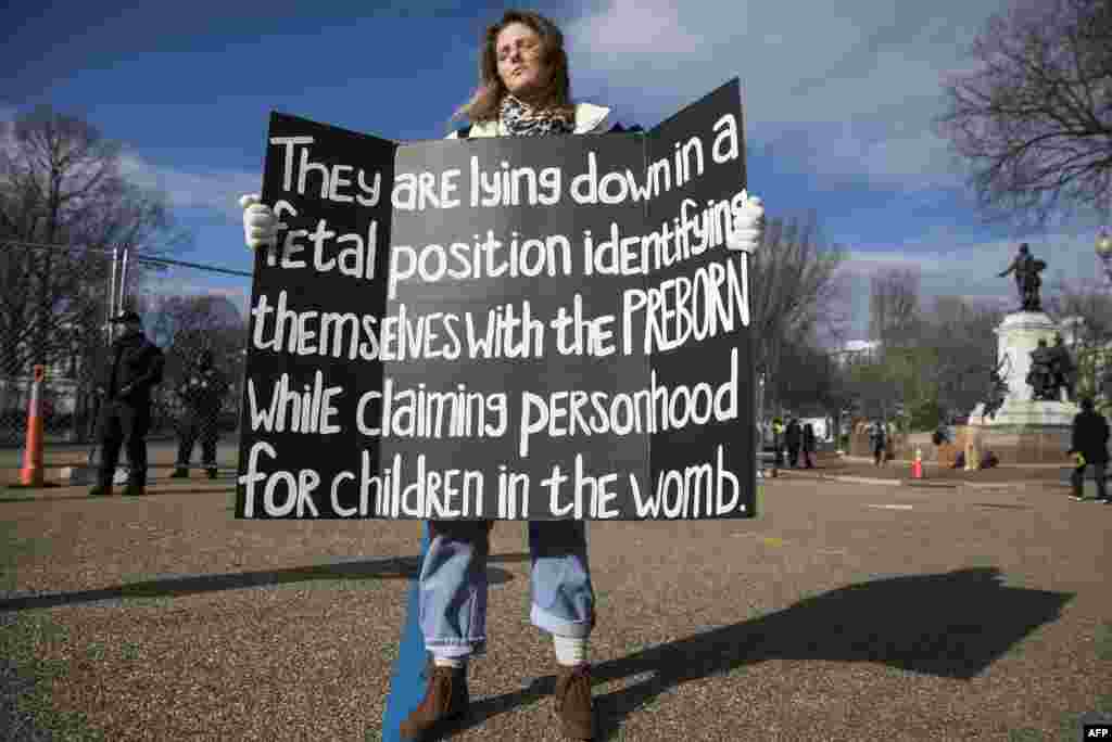 A demonstrator holds a sign during a "die-in" in front of the White House, Jan. 27, 2017, in Washington, D.C.