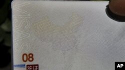 A Chinese man holds up a Chinese passport with details on a page that shows dashes which include the South China Sea as part of the Chinese territory outside a passport office in Beijing, Nov. 23, 2012. 
