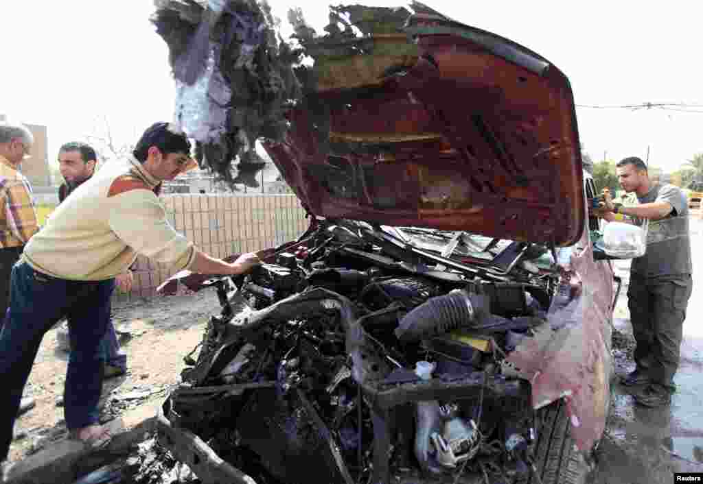 A man inspects a damaged vehicle at the site of bomb attack in Baghdad, March 5, 2014.