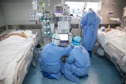 FILE - Medical staff treat COVID-19 patients at a hospital in Wuhan, in China's central Hubei province, March 19, 2020.