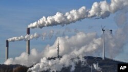 This Jan. 16, 2020 file photo shows a Uniper energy company coal-fired power plant and a BP refinery beside a wind generator in Gelsenkirchen, Germany.