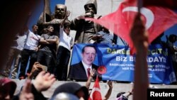 Para pendukung Presiden Erdogan mengangkat spanduk dengan foto Presiden Turki Tayyip Erdogan selama unjuk rasa pro-pemerintah (19/7). Istanbul, Turki (foto: REUTERS/Alkis Konstantinidis)