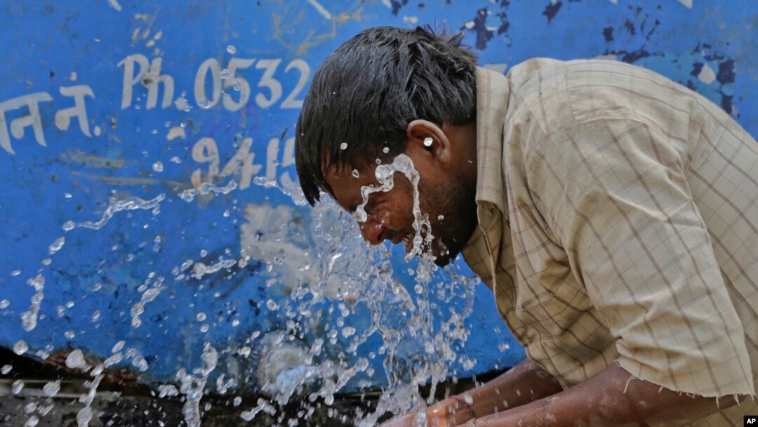 FILE - An Indian worker splashes water on his face as he tries to cool himself on a hot summer day in Allahabad, India.