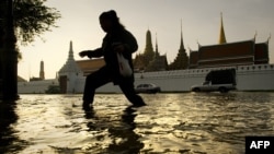 រូបភាពឯកសារ៖ ស្រ្តី​ម្នាក់ដើរ​កាត់​ទឹក​លិចនៅ​ខាង​មុខព្រះបរមរាជវាំង​ក្នុង​ទីក្រុង​បាងកក។