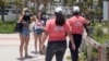 Una mujer se pone la máscara de protección bajo la indicación de los "Embajadores del distanciamiento social" en las áreas reabiertas de una playa de Miami. Junio 10 de 2020.