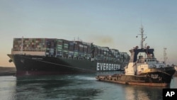 In this photo released by Suez Canal Authority, the Ever Given, a Panama-flagged cargo ship, is pulled by one of the Suez Canal tugboats, in the Suez Canal, Egypt, March 29, 2021. 