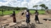 Members of a family stand next to their grass-hut dwelling which was destroyed by the police at Manzou Farm in Mazoe, north of Harare, in Zimbabwe, Jan. 15, 2015.