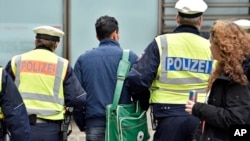 Police lead away a man at the main train station, Jan. 12, 2016, in Cologne, Germany. New Year’s Eve sexual assaults and robberies in Cologne were blamed largely on foreigners and pushed the discussion about the migration crisis.