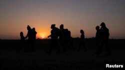Migrantes de El Salvador y Honduras caminan hacia el muro fronterizo después de cruzar el río Grande, en Penitas, Texas, el 26 de marzo de 2021.