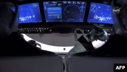 Esta captura de fotogramas de la NASA muestra la nave espacial Crew Dragon de SpaceX con los astronautas Douglas Hurley y Robert Behnken mirando una vista infrarroja de la Estación Espacial Internacional después de desacoplarla el 1 de agosto de 2020.