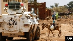 Un jeune soudanais traverse une route à dos d’âne devant une auto-blindée de la mission de l'Union des Nations Unies et de l'Union africaine à Darfour (Minuad), Soudan, 19 juin 2017.