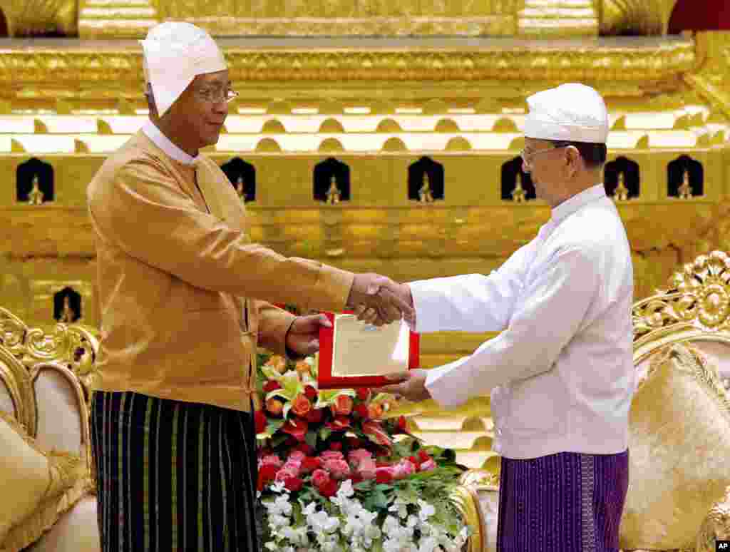 Myanmar's new president Htin Kyaw, left, receives the presidential seal from outgoing president Thein Sein, during a handover ceremony in Naypyitaw, March 30, 2016.
