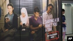 A commuter walks past an advertisement discouraging the dissemination of fake news at a train station in Kuala Lumpur, Malaysia, March 29, 2018.