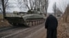 Un sacerdote saluda mientras un tanque separatista aparentemente regresa a su base, cerca de Donetsk.