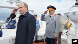 Russian President Vladimir Putin reviews a Navy parade in Baltisk, western Russia, July 26, 2015, during celebrations for Russian Navy Day. Defense Minister Sergei Shoigu stands at right.