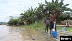 wadansu yara suna tsaye kusa da bututun mai da aka yi watsi da su.al, Yenagoa, babban birnin jihar Delta.