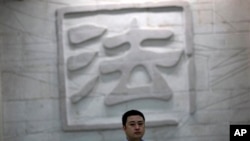 Seorang pria melewati tulisan berbahsa Mandarin yang berarti "Hukum" dalam gedung pengadilan di Kota Hefei, provinsi Anhui, China (Foto: dok). Pemerintah China tengah menyelidiki mantan wakil gubernur wilayah ini karena diduga terlibat kasus korupsi.