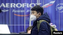 资料照：一名戴着口罩的旅客在俄罗斯谢列梅捷沃国际机场的俄罗斯航空公司订票柜台旁。（2020年2月4日）