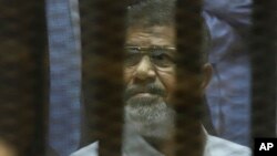 Mantan Presiden Mesir Mohammed Morsi duduk di balik pembatas kedap suara di ruang persidangan Akademi Polisi Nasional di Kairo, 21 April 2015. 