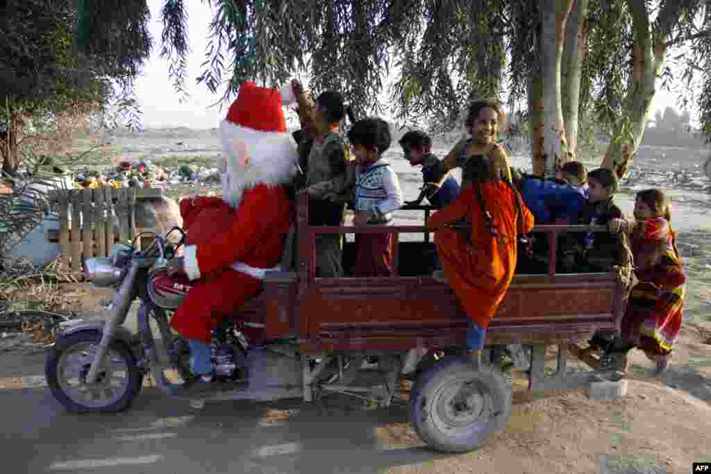 បុរសម្នាក់ស្លៀកពាក់ជា Santa Claus ហើយឌុបក្មេងនៅក្នុង តុកតុកជាយក្រុង Najaf ប្រទេសអ៊ីរ៉ាក់។
