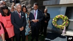 Rev. Julius Scruggs, second from left, leads people in prayer during a wreath laying ceremony at the 16th Street Baptist Church