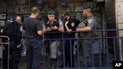 Polisi Israel memeriksa dokumen seorang pria yang berusaha memasuki kota tua Yerusalem hari Minggu (4/10). Israel mencabut peraturan keamanan ketat hari Selasa 6/10.