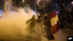 Manifestantes se refugian del gas lacrimógeno lanzado por la policía para dispersarlos en la Plaza de San Martín en Lima. Los manifestantes se rechazan a reconocer al nuevo gobierno interino del Perú.